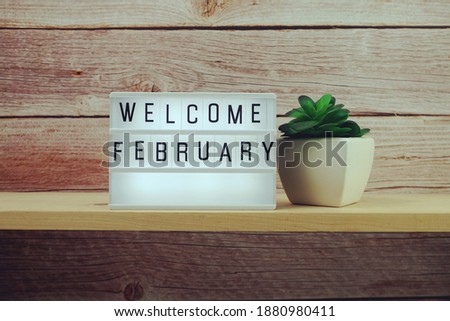 Welcome February word in light box on wooden shelves background