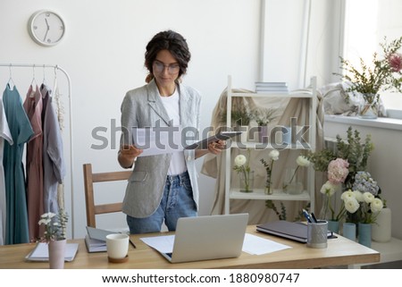 Choosing only the best. Young woman tailor designer comparing samples of textile colors offered by suppliers. Professional flower arranger pondering thinking making choice preparing to order materials