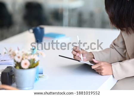 Cropped shot of female designer  hand holding stylus pen drawing on digital tablet at her workstation.