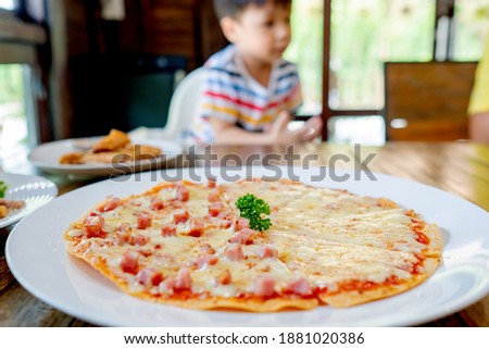 Cute asian kid boy eating Pizza by self. Background. Copy space. Soft focus.