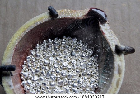A ceramic crucible or melting pot with grains of sterling silver 925 for jewelry making after hand smelting in a workshop. One of the two major precious metals on the market. Royalty-Free Stock Photo #1881030217