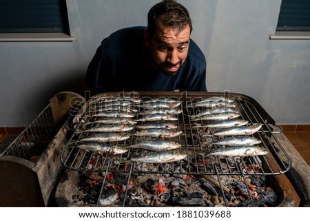 Man cooking a barbecue of fresh sardines on a charcoal barbecue. Healthy food concept