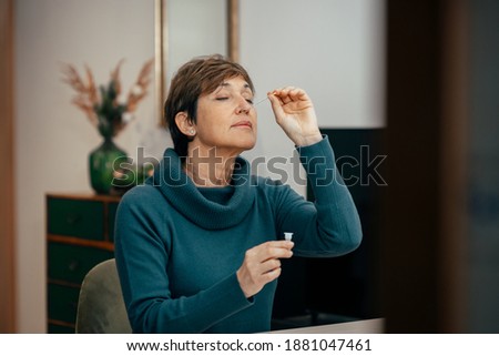 Portrait Senior woman sitting, doing a auto test for COVID-19 at home with Antigen kit. Introducing nasal swab test for possible infection of Coronavirus. Medicine and health-related services online.