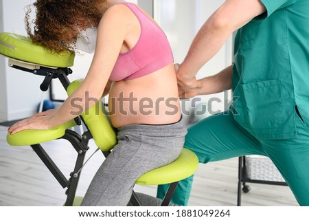 Male physiotherapist cures back pain of a pregnant woman. High quality photo