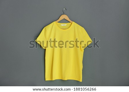 Yellow plain shirtsleeve cotton T-Shirt mockup on wooden hanger Gray background Organic cotton manufacture Space for text logo design
