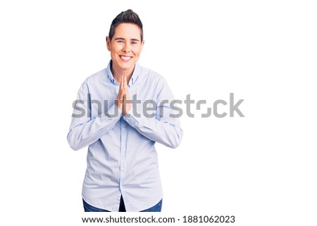 Young woman with short hair wearing business clothes praying with hands together asking for forgiveness smiling confident. 