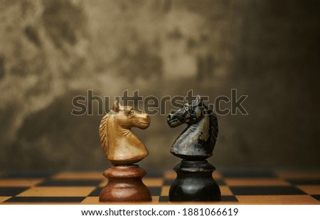 Wooden chess pieces knights facing each other on a vintage chessboard. Confrontation and rivalry concept, selective focus. Royalty-Free Stock Photo #1881066619