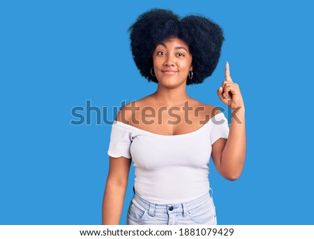 Young african american girl wearing casual clothes pointing finger up with successful idea. exited and happy. number one. 