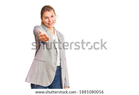 Young beautiful blonde woman wearing elegant jacket smiling cheerful offering palm hand giving assistance and acceptance. 
