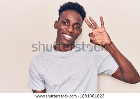 Young african american man wearing casual clothes smiling positive doing ok sign with hand and fingers. successful expression. 
