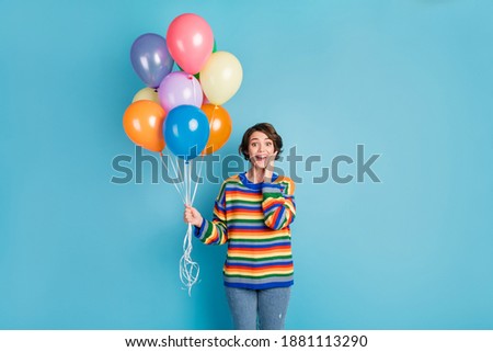 Photo portrait of shocked girl touching face cheek holding balloons in one hand isolated on pastel blue colored background