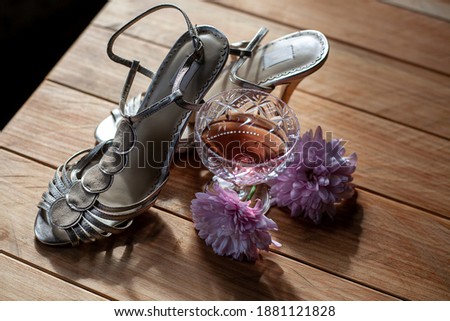 bridal wedding shoes, lilac chrysanthemums and glass goblet of rose wine on wooden background