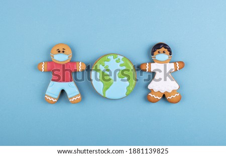 two gingerbread man medics in a mask girl and boy, gingerbread planet earth in the middle. the coronavirus pandemic. thank you to the medical staff, the doctor, the nurses