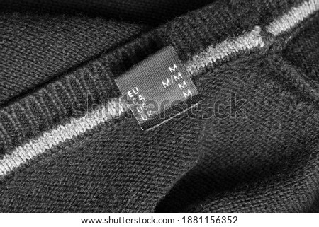 Size M clothing label on black knit background
