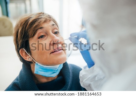 Close up of the face of senior female patient being tested for Covid-19 with a nasal swab, by a health Professional protected with gloves and PPE suit. Rapid Antigen Test during Coronavirus Pandemic. Royalty-Free Stock Photo #1881164653