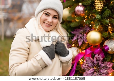 holidays and people concept - beautiful happy young woman over christmas tree lights in winter evening