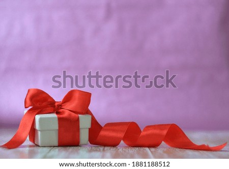 Valentines day concept. A white square paper gift box with a red ribbon.