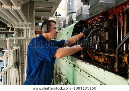 Marine engineer officer controlling vessel enginesand propulsion in engine control room ECR. Ship onboard maintenance Royalty-Free Stock Photo #1881193150