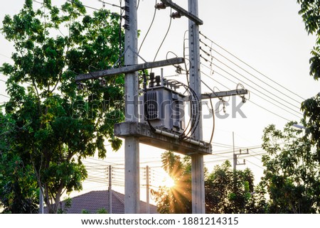 High voltage tranformer for the village, Distribution high voltage with green tree on sunset sky Royalty-Free Stock Photo #1881214315