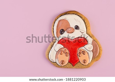 Gingerbread shaped as sloth with big red heart in his arms, ginger cookies on a pink background