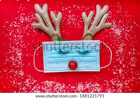 Coronavirus festive winter background mask with eyes, deer horns, snowflakes, snow. The concept of a pandemic during the Christmas holidays. High quality photo