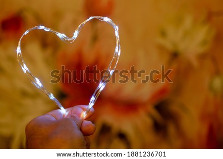 hand holding wire lamp heart, with blurred background. Valentine's Day
