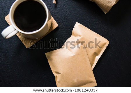 Top view image of Black coffee in a mug with mock up design coffee bean package on a black table