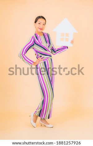 Portrait beautiful young asian woman with home or house sign paper on color background