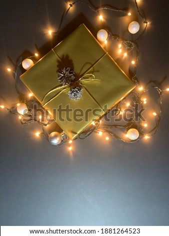 Gift in festive packaging among christmas lights, copy space