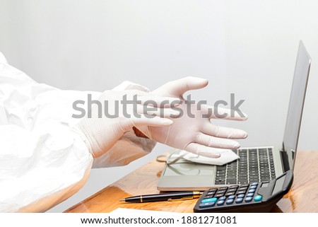 business men wear rubber gloves to working  with laptop at wooden table