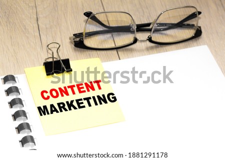 Text CONTENT MARKETING on a notepad with eyeglasses and text documents. Could be for business, financial and marketing concepts