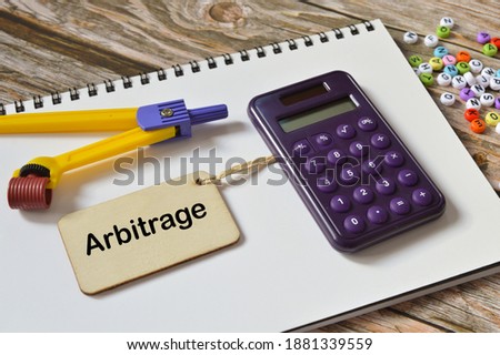 Selective focus of calculator, alphabet beads, notebook, math compass and wooden board written with text ARBITRAGE. Business concept. Royalty-Free Stock Photo #1881339559