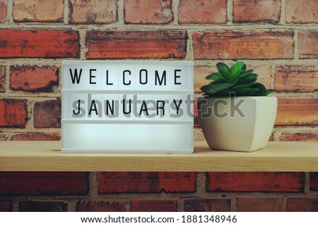 Welcome January word in light box on wooden shelves background