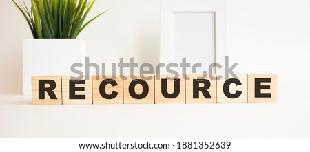 Wooden cubes with letters on a white table. The word is RECOURCE. White background.