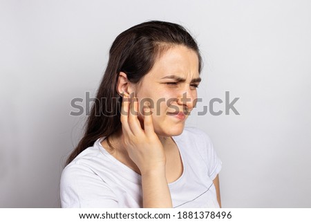 The woman has a sore ear - infection, inflammation from infection and otitis. Perforation ruptured the eardrum. Arthritis of the temporal lower jaw joint, osteoarthritis and pain in the jaw Royalty-Free Stock Photo #1881378496