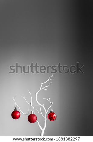 Red Christmas balls on white branch on light and dark background. Red Christmas balls in a cup. Merry Cristmas greeting card with Christmas decoration. 