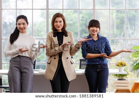 Three beautiful and self-confident businesswomen standing in office and showing hand sign language skill in the same action