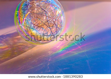 Rainbow Christmas ball on color background against blurred fairy lights, space for text. Christmas Abstract lights in Festive Background. Christmas Concept