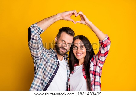 Portrait of lovely cheery couple showing up heart symbol shape idyllic isolated over bright yellow color background