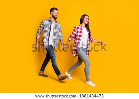 Photo portrait full body view of husband and wife holding hands walking isolated on vivid yellow colored background