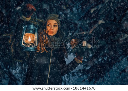 Young girl with lantern in winter forest fairy tale, book cover