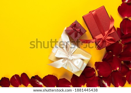flat lay, several beautifully packed boxes lie in a shopping basket on an orange background near rose petals. Concept to celebrate valentine's day. Copy space.