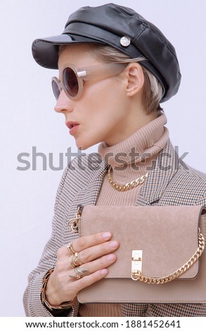Paris Lady in fashion elegant outfit. Trendy cap and sunglasses. Beige velvet clutch. Style in details. Fall winter season. Vintage, retro lover