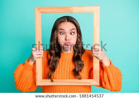Photo of young girl hold photo frame grimacing fooling hold breath isolated over turquoise color background