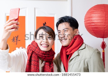 Loving asian young couple making a selfie in front of the door with spring festival couplets