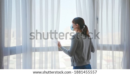 rear view asian young woman wearing face mask stay isolation at home for self quarantine due to epidemic of COVID19 - she looks out the window Royalty-Free Stock Photo #1881455557