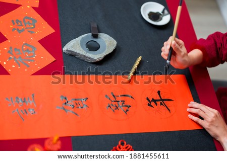 Close up of writing spring festival couplets to celebrate Chinese holidays with word meaning happy new year  Royalty-Free Stock Photo #1881455611