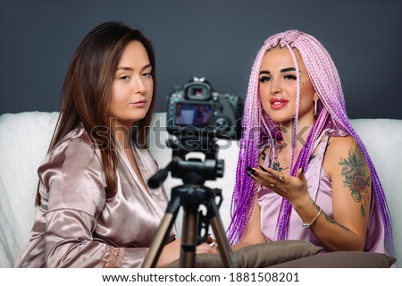 Young modern women in front of camera in studio. Grey background. Online beauty and fashion blog 