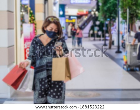 Concept blurry image A young woman wearing a blue mask is shopping malls, lifestyle, COVID-1962.