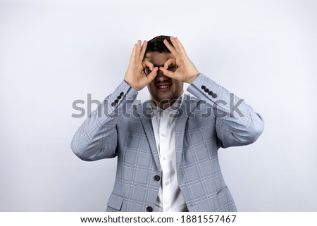 Business young man wearing a casual shirt over white background doing ok gesture shocked with smiling face, eye looking through fingers